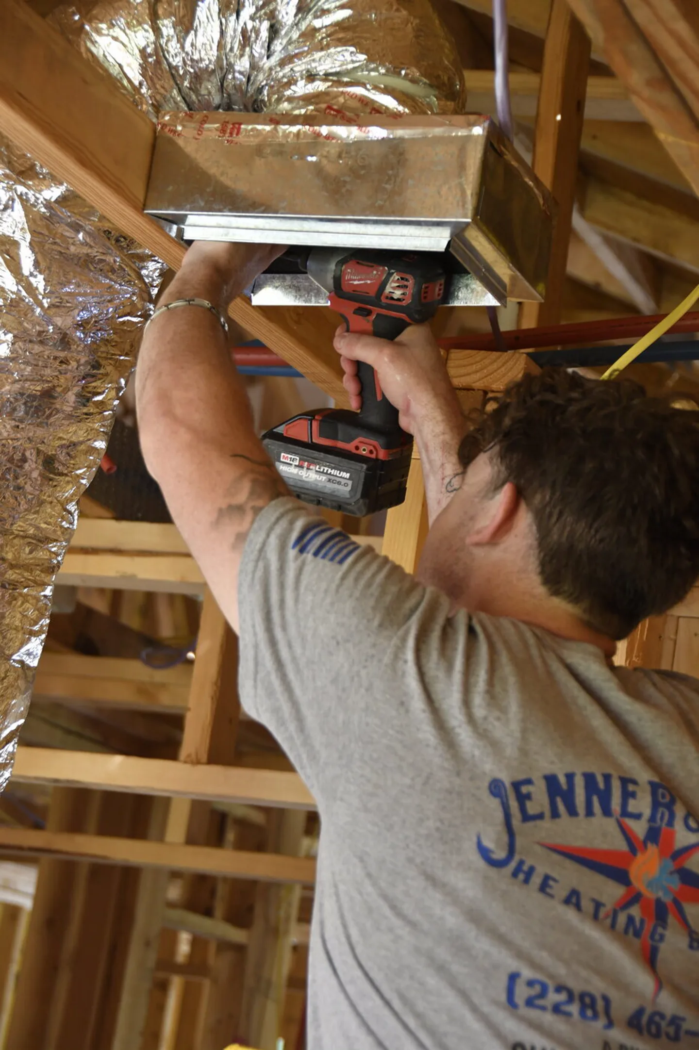 Technician securing a supply box in the ceiling framing
