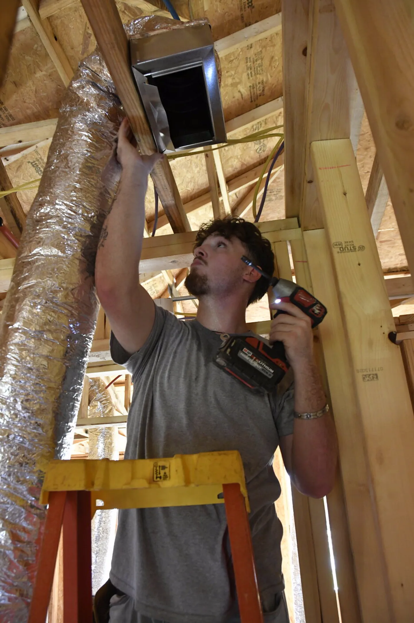 Technician installing a duct box from a ladder