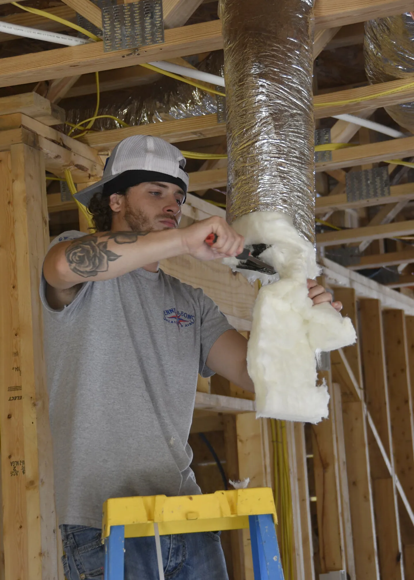 Technician fitting flexible ductwork in a framed home